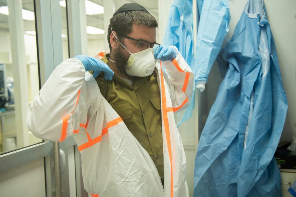An IDF soldier dons protective gear at a military lab researching treatment for coronavirus (Photo: IDF Spokesperson's Unit) מעבדה לזיהוי נגיף הקורונה בצה"ל
