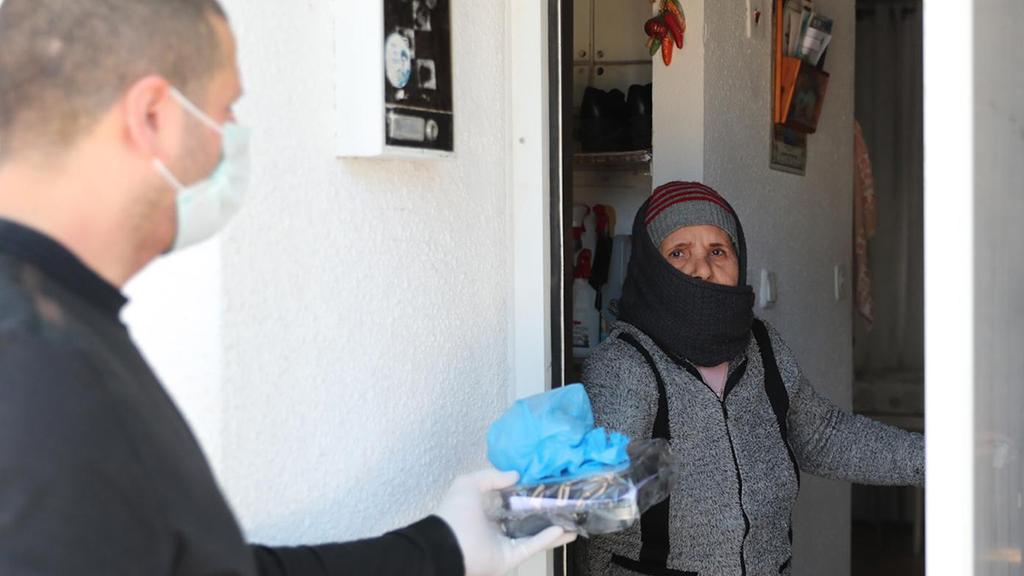 A volunteer delivers food to an elderly woman living alone (Photo: GPO) מבצע חלוקת המזון לקשישים בצל התפשטות נגיף הקורונה