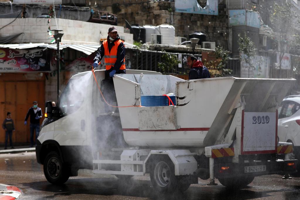 Palestinian municipality employees spray disinfectant in the West Bank town of Hebron, 24 March 2020 (Photo: EPA) Palestinian municipality employees spray disinfectant in the West Bank town of Hebron, 24 March 2020