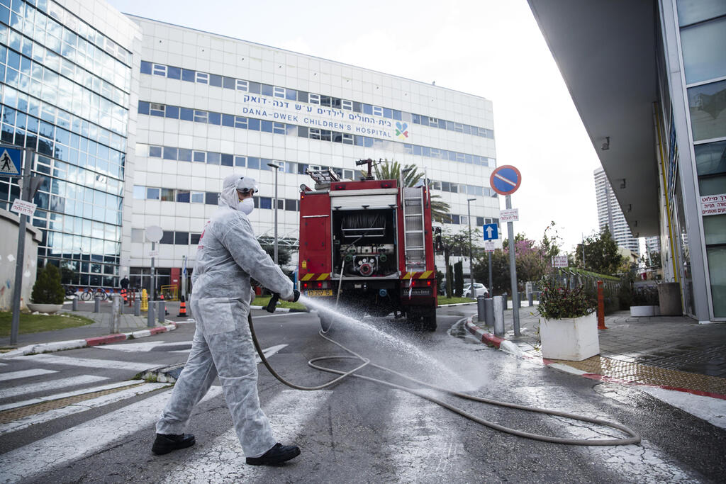Sanitation worker sprays disinfectant against coronavirus outside Sourasky Medical Center in Tel Aviv (Photo: Gettyimages) איכילוב