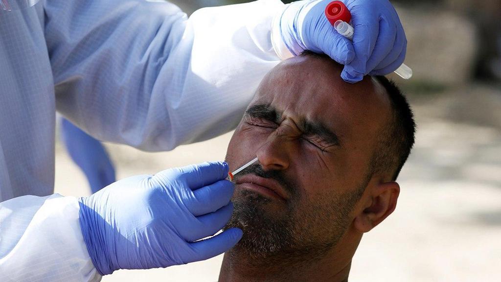 A Palestinian worker being tested upon returning to the West Bank from Israel (Photo: EPA) בדיקת קורונה מטוש מטושים פלסטינים תרקומיא חברון