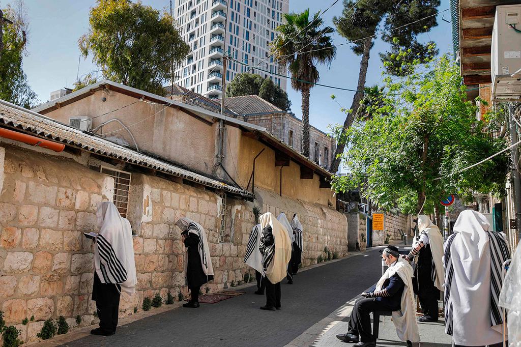 Haredi men practice social distancing as they pray outside a synagogue in Jerusalem (Photo: AFP) מתפללים ליד בית כנסת סגור ב ירושלים