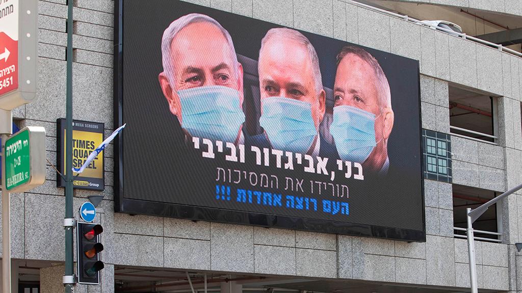 A banner in Ramat Gan calls on Benjamin Netanyahu, Avigdor Liberman and Benny Gantz to 'take off your masks, the people want unity' (Photo: AP) שלט חוצות