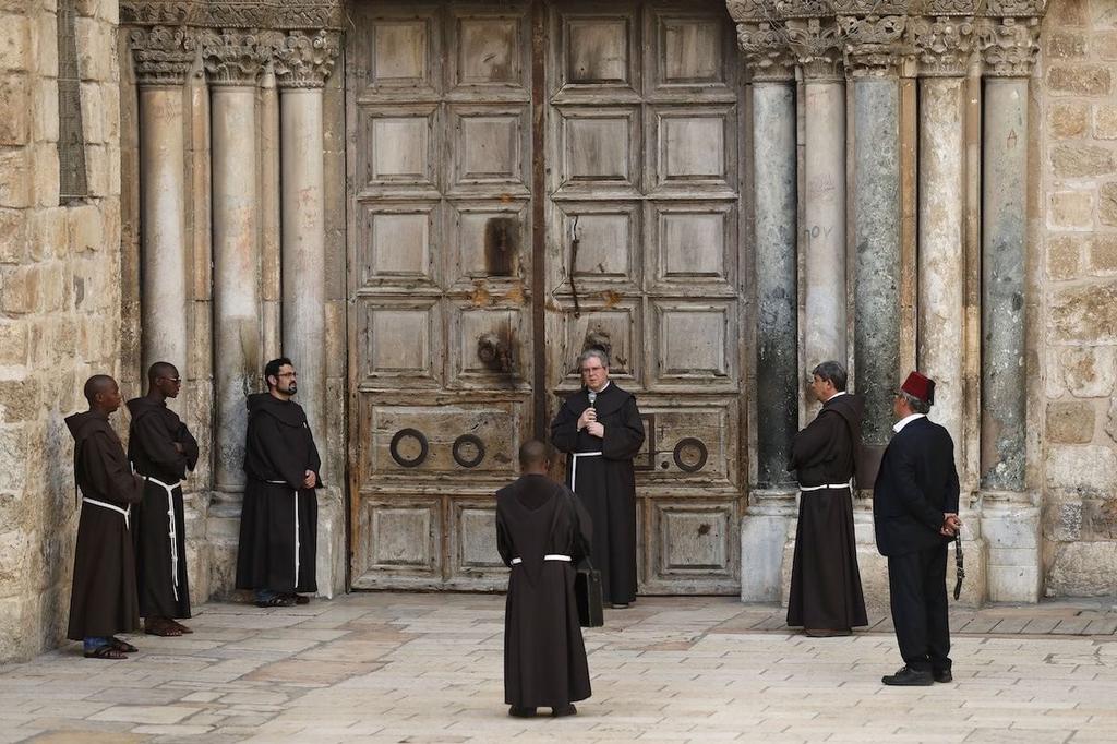 Franciscan monks pray in front of the closed door of the Church of the Holy Sepulchre 