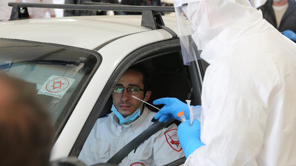 A healthcare official carries out a coronavirus test on a medic at a 'drive through' site in Jerusalem (Photo: Alex Kolomoisky) מתחם " היבדק וסע" בירושלים
