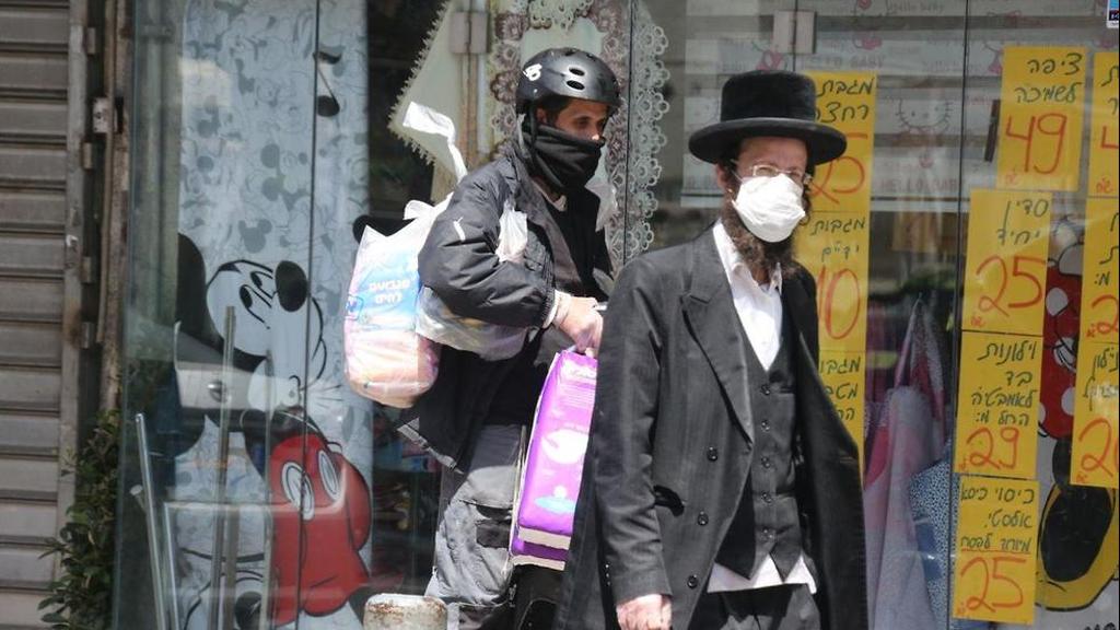 A Haredi man walks past a police officer enforcing coronavirus restrictions in Bnei Brak (Photo: Moti Kimchi) בני ברק בצל משבר הקורונה