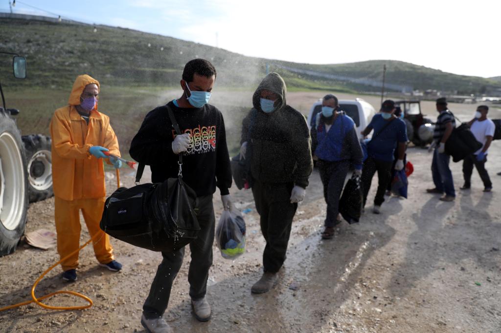An employee of the Palestinian health ministry sprays disinfectant on workers crossing the checkpoint of Tarqumiya, near the West Bank town of Hebron (Photo: EPA) An employee of the Palestinian health ministry sprays disinfectant on workers crossing the checkpoint of Tarqumiya, near the West Bank town of Hebron