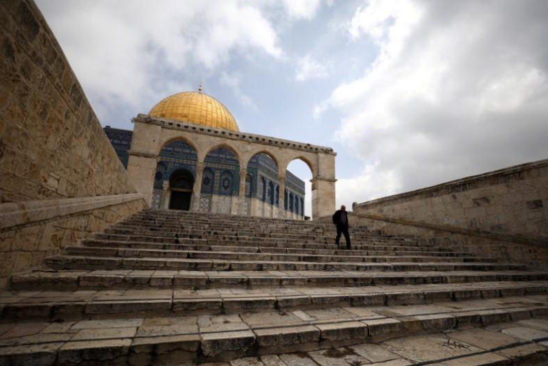 A man walks in front of the Dome of the Rock 
