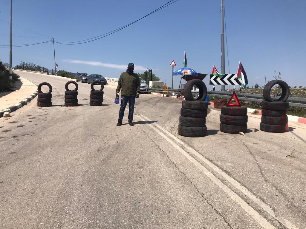 A volunteer stands at one of the entrances to the West Bank city of Sinjil, checking and sanitizing cars amid the coronavirus pandemic 