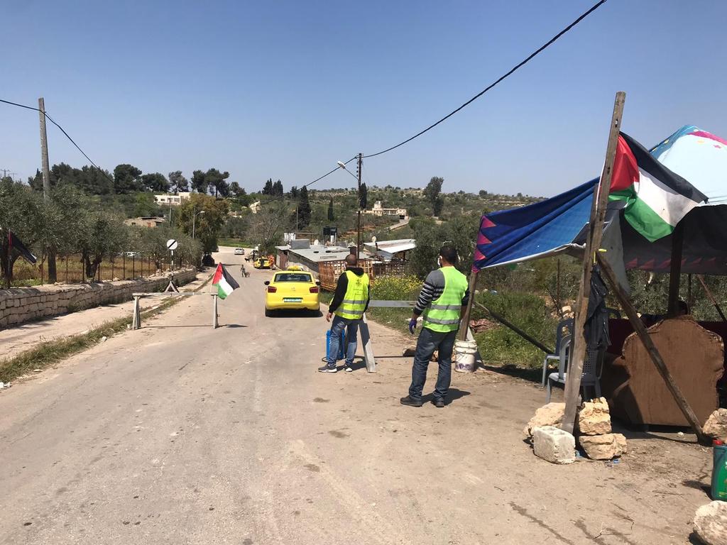Volunteers check cars passing through the West Bank city of Sinjil during the coronavirus pandemic 