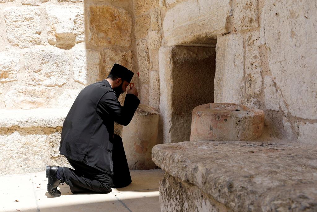 A priest kneels outside the Church of the Nativity closed due to COVID-19 (Photo: Reuters) A priest kneels outside the Church of the Nativity closed due to COVID-19