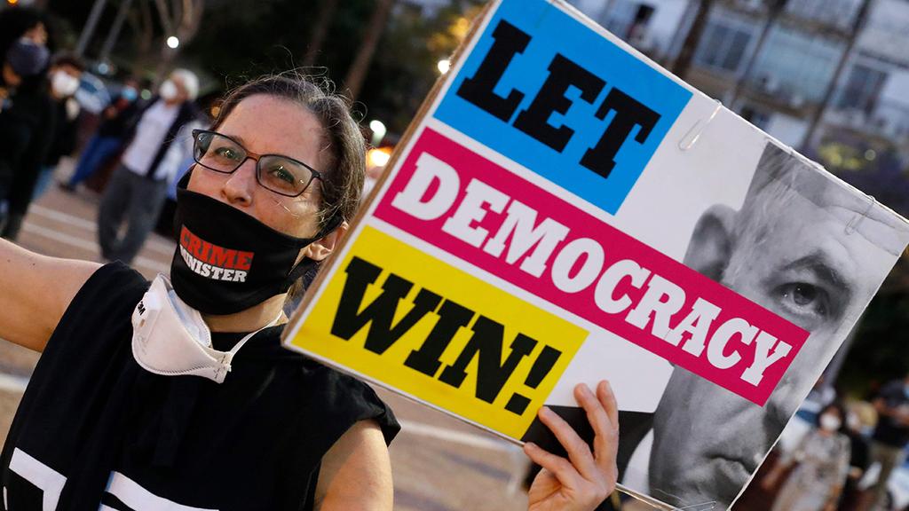 A demonstrator at an anti-Netanyahu protest in Tel Aviv (Photo: AFP) מחאת הדלגים השחורים בכיכר רבין