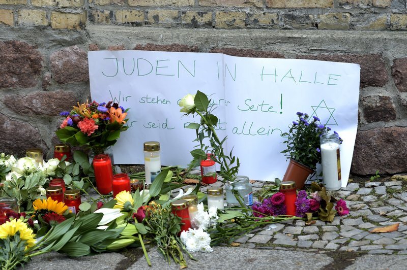 Candles and flowers placed in front of a synagogue in Halle, after a heavily armed assailant ranting about Jews tried to force his way into the synagogue in Germany; Sign reads, 'Jews in Halle - We stay next to you! You are not alone' 