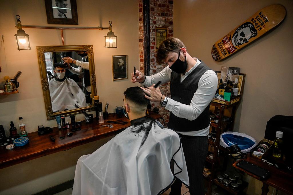 A barber in Athens and his client wear face masks to protect against coronavirus (Photo: AFP) מספרה אתונה יוון הקלות ב סגר קורונה
