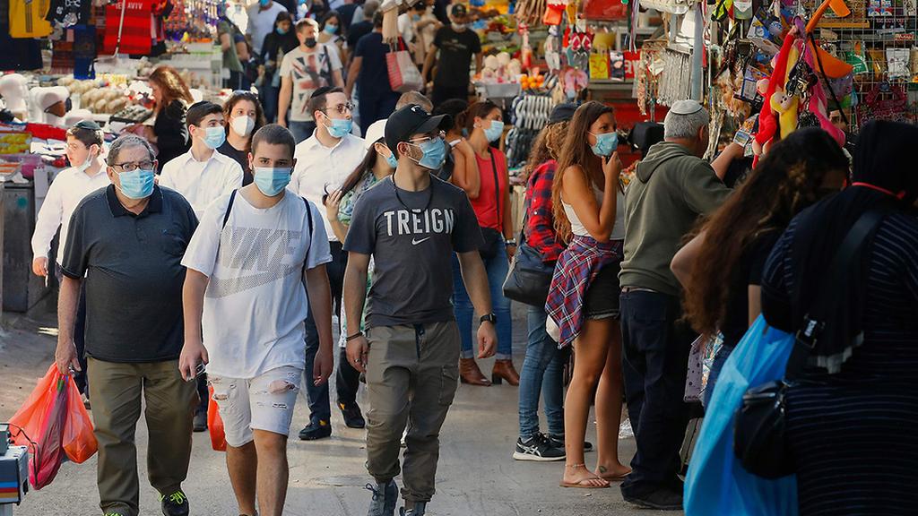 Tel Aviv's Carmel Market full after lifting regulations (Photo: AFP) קונים עם מסכות בשוק הכרמל