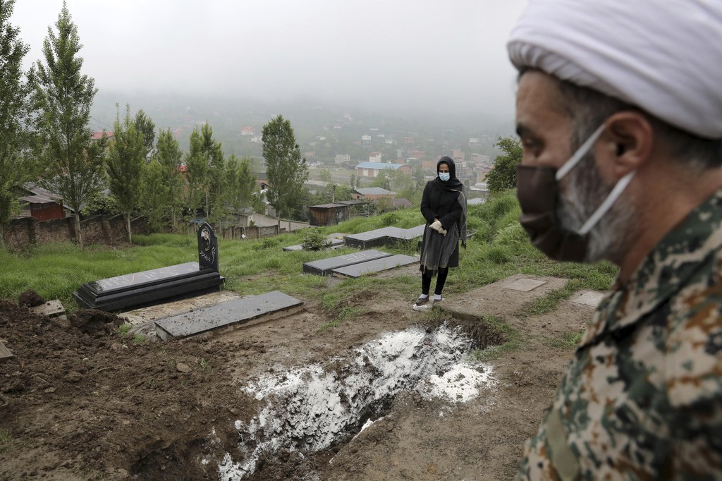 A woman wearing mask and gloves prays over the grave of her mother   who died from COVID-19 at a cemetery on the outskirts of Babol, northern Iran 