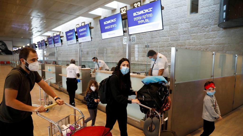 Passengers wearing masks push trolleys at the departures terminal at Ben Gurion Airport 
