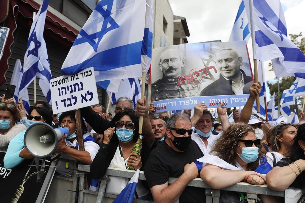 Supporters of Benjamin Netanyahu protest outside Jerusalem District Court. One of the posters compares the prime minister to Alfred Dreyfus (Photo: AFP) תומכי נתניהו