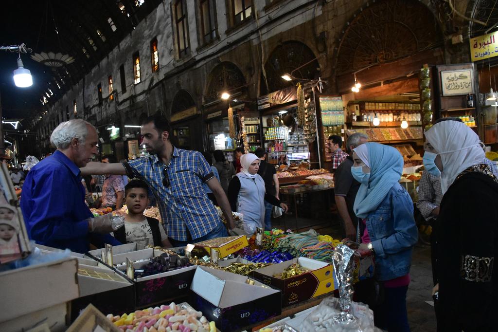 People buy chocolate and candies at al-Bzouriyeh market ahead of the Eid al-Fitr in the old city of Damascus 