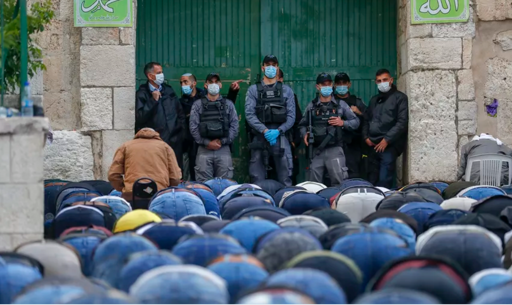 Israeli security forces clad in masks due to the coronavirus pandemic look on as Muslim worshipers gather to attend the prayers of Eid al-Fitr outside the closed Aqsa mosque complex in Jerusalem's old city 