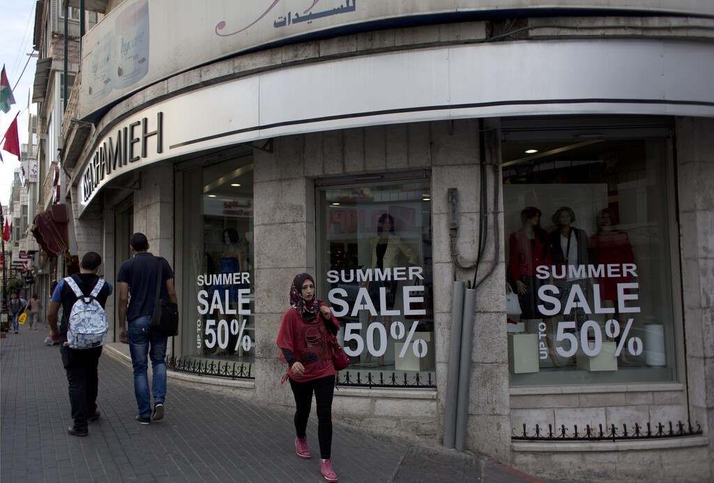 Palestinians walk past a boutique in the West Bank city of Ramallah