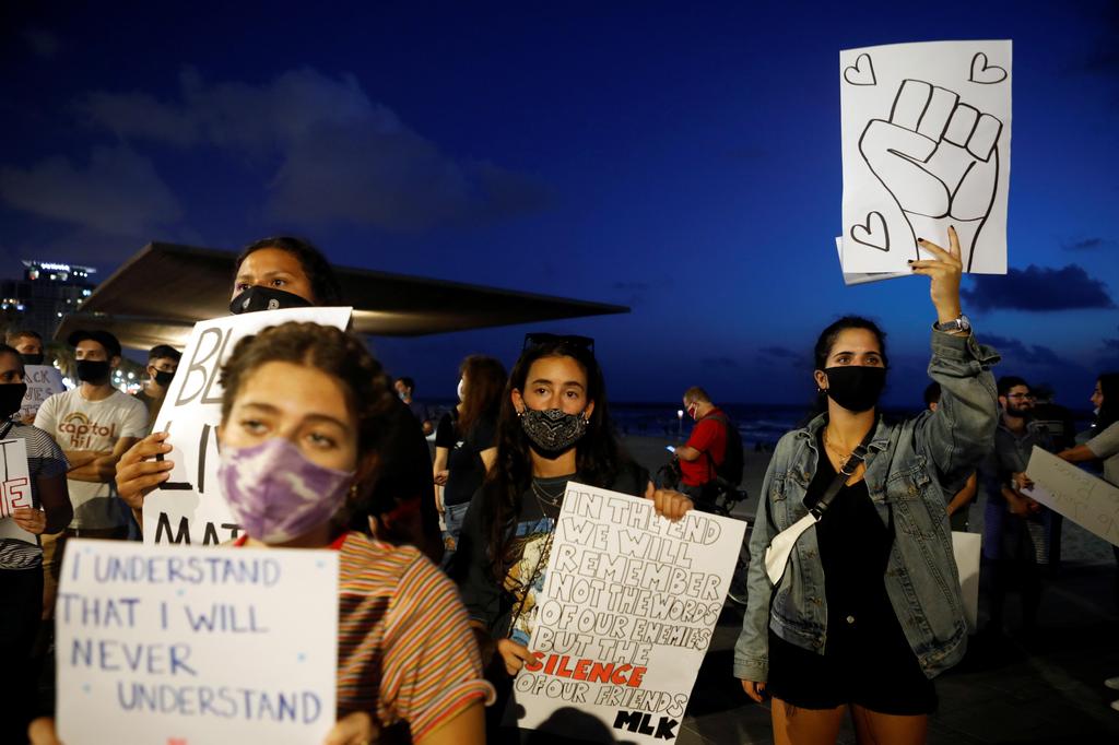 People hold placards as they protest in solidarity with those in the United States protesting police brutality and the death in Minneapolis police custody of George Floyd, in Tel Aviv 