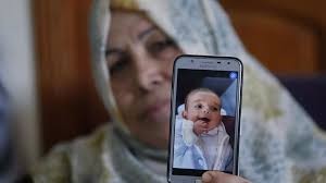 The grandmother of nine months old Palestinian baby Omar Yagi displays a picture 