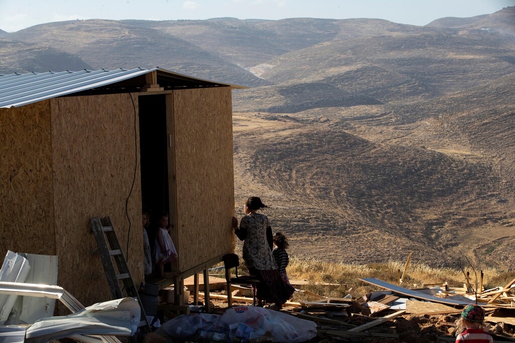 A settler and children stand next to a temporary structure in the West Bank outpost of Maoz Ester 