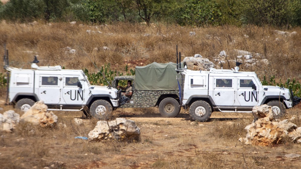 Lebanese soldiers on patrol drive by UN vehicles on the border with Israel, July 28, 2020 
