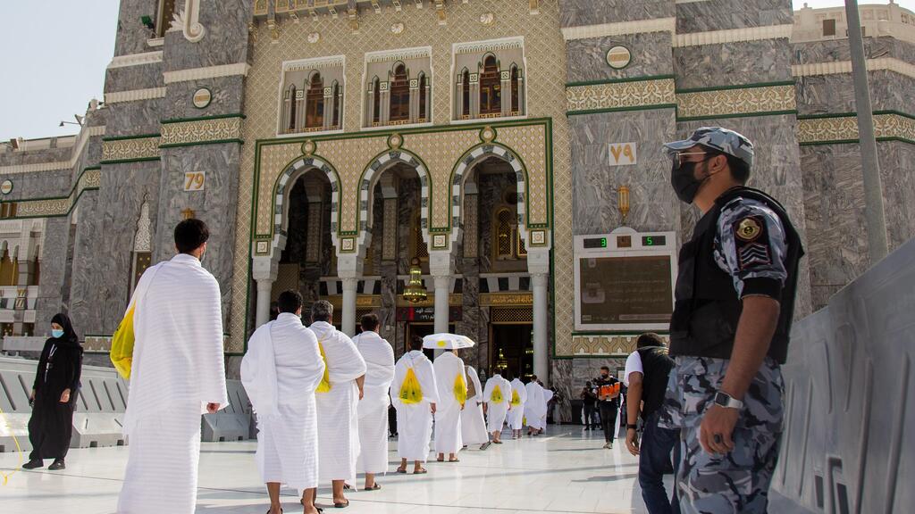 Security personnel stand near pilgrims maintaining social distancing outside as they enter the Grand Mosque in Mecca on the first day of Hajj,  July 29, 2020 