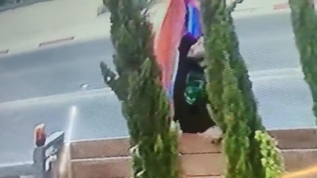 האלמוני משתמש בסכין כדי להסיר את הדגל תליית דגלי גאווה שרחבי רמת גן