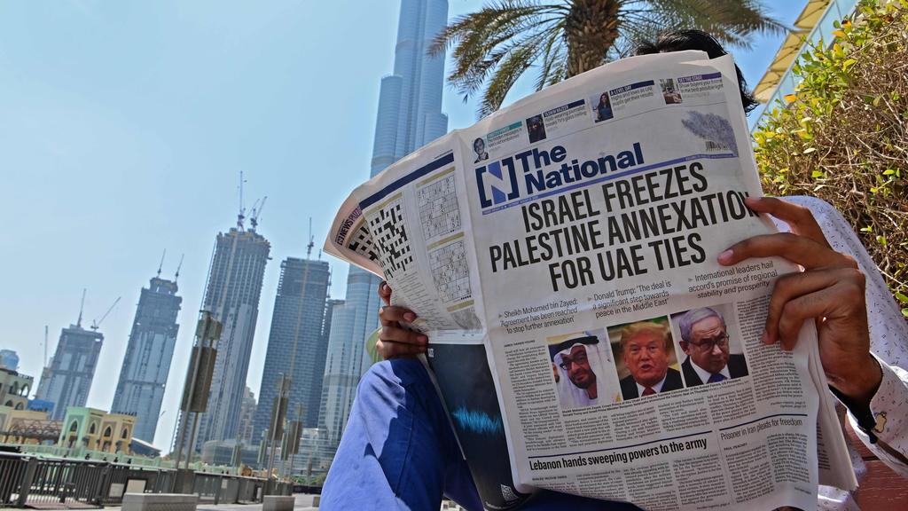  man reading a copy of  the UAE-based The National newspaper regarding the UAE-Israel agreement 