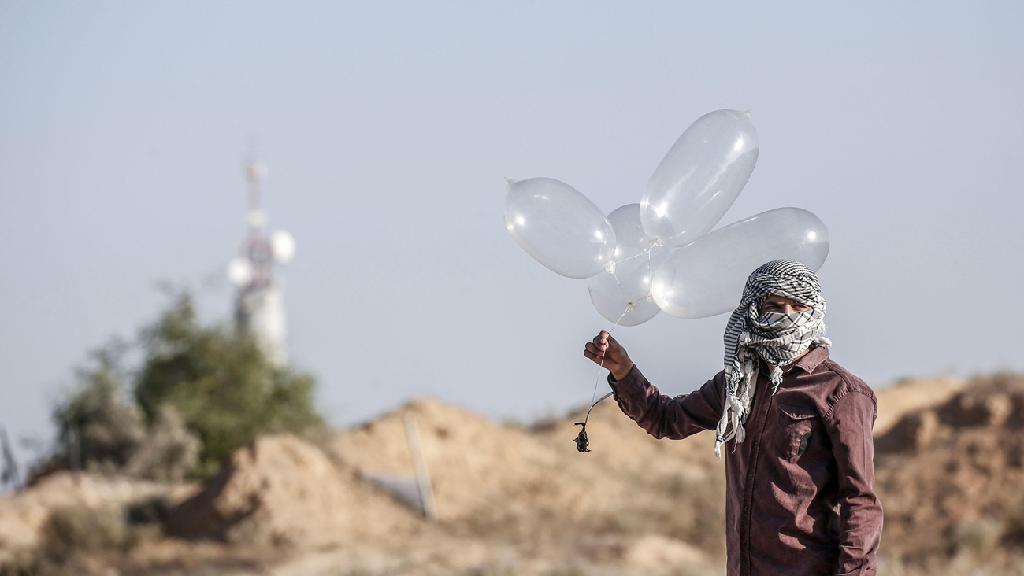  A terrorist in Gaza prepares to launch an incendiary device towards Israel using what appear to be condoms filled with helium 