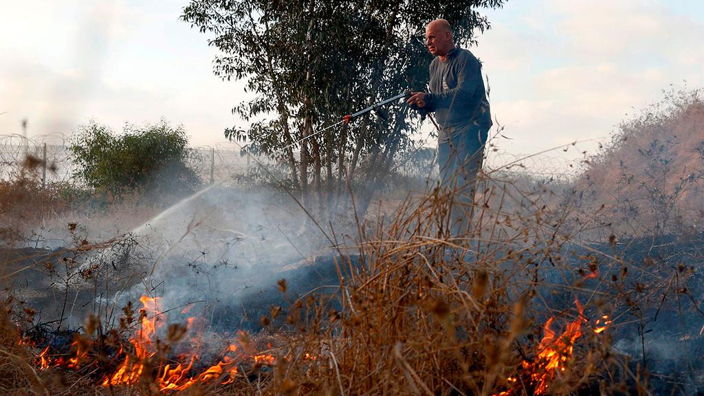 צילום: AFP עובד רשות הטבע והגנים מכבה שריפה ליד קיבוץ בארי