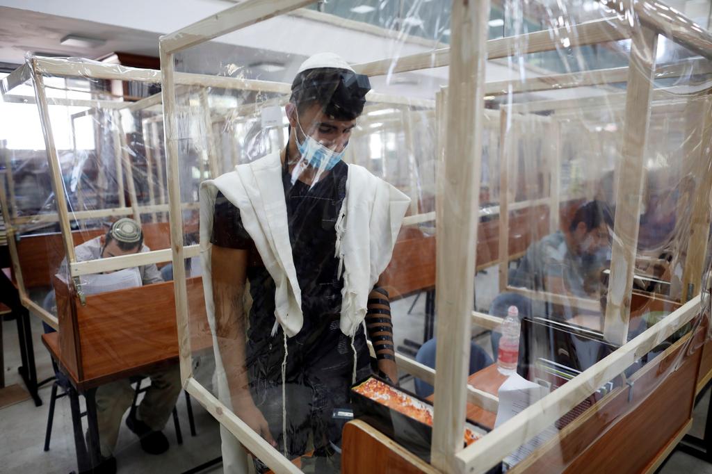 Jewish seminary students study and pray at desks fitted with plastic sheets to protect them from the spread of coronavirus 