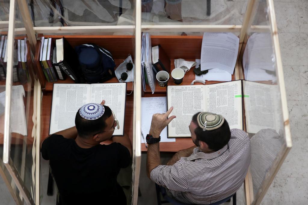 Jewish seminary students study at desks fitted with plastic sheets to protect them from the spread of the coronavirus disease 