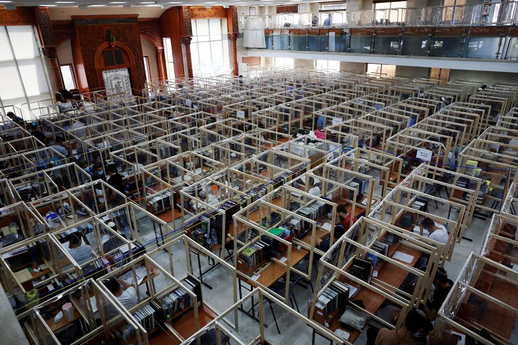 Jewish seminary students study at desks fitted with plastic sheets to protect them from the spread of the coronavirus disease 