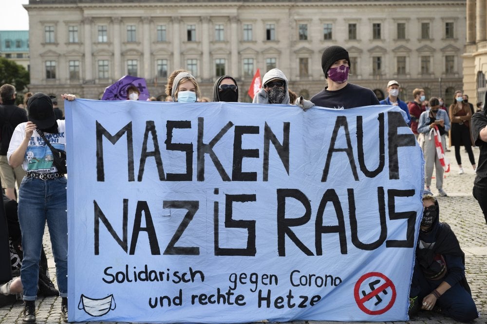 Counter-demonstrators of a rally against the coronavirus measures gather and hold out a banner reading 'Masks on Nazis out' in Berlin, Germany (Photo: AP) Counter-demonstrators of a rally against the Corona measures gather and hold out a banner reading "Masks on Nazis out" in Berlin, Germany