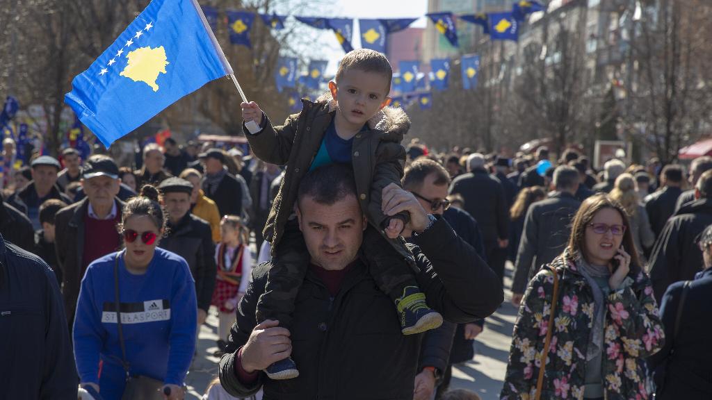 A father holds his son waving Kosovo's flag as they celebrate the 12th anniversary of the country's independence, in the capital Pristina, Monday, Feb. 17, 2020