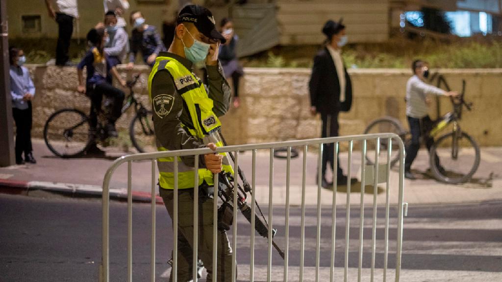 שוטר מג"ב מציב מחסום בשכונה בבית שמש בתחילת השבוע (צילום: AP) שוטר מג"ב מציב מחסום בשכונה בבית שמש סגר לילי קורונה