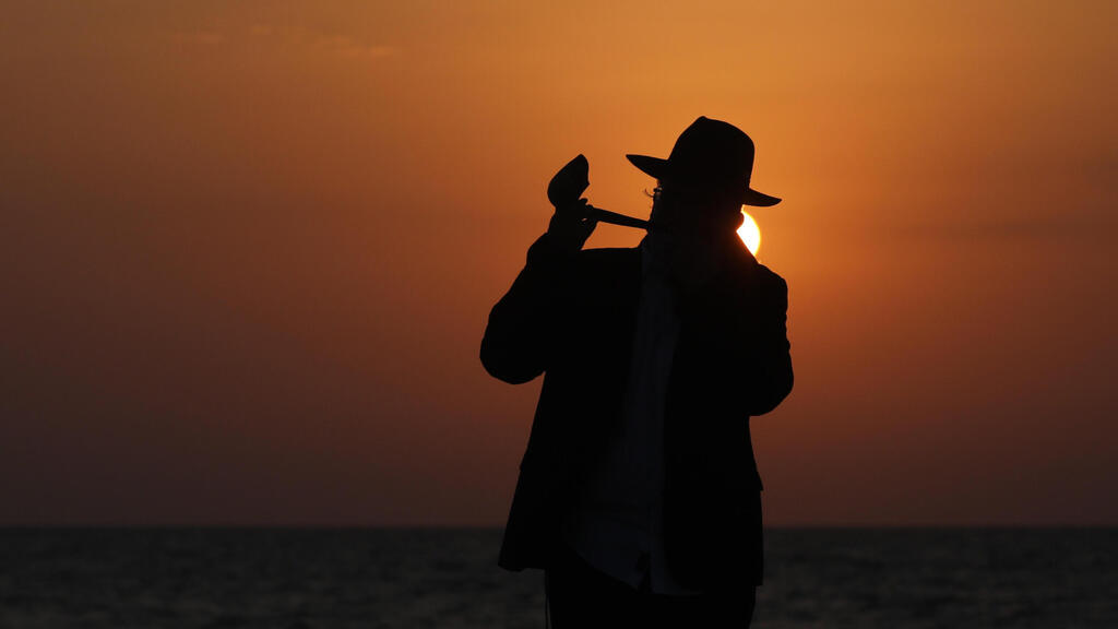 An Orthodox Jewish man blows the shofar as he performs a Tashlich Prayer at the beach during lockdown at the Jewish holiday of Rosh Hashanah in Tel Aviv