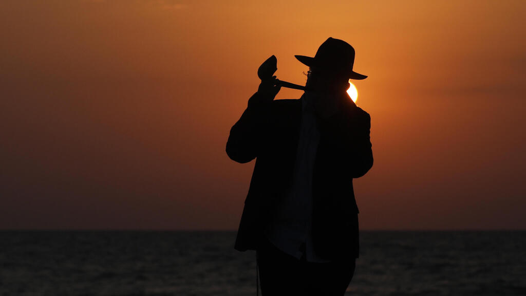 An Orthodox Jewish man blows the shofar as he performs a Tashlich Prayer at the beach during lockdown at the Jewish holiday of Rosh Hashanah in Tel Aviv