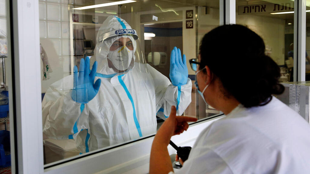 Staff talk through protective glass at a coronavirus ward in an Israeli hospital 