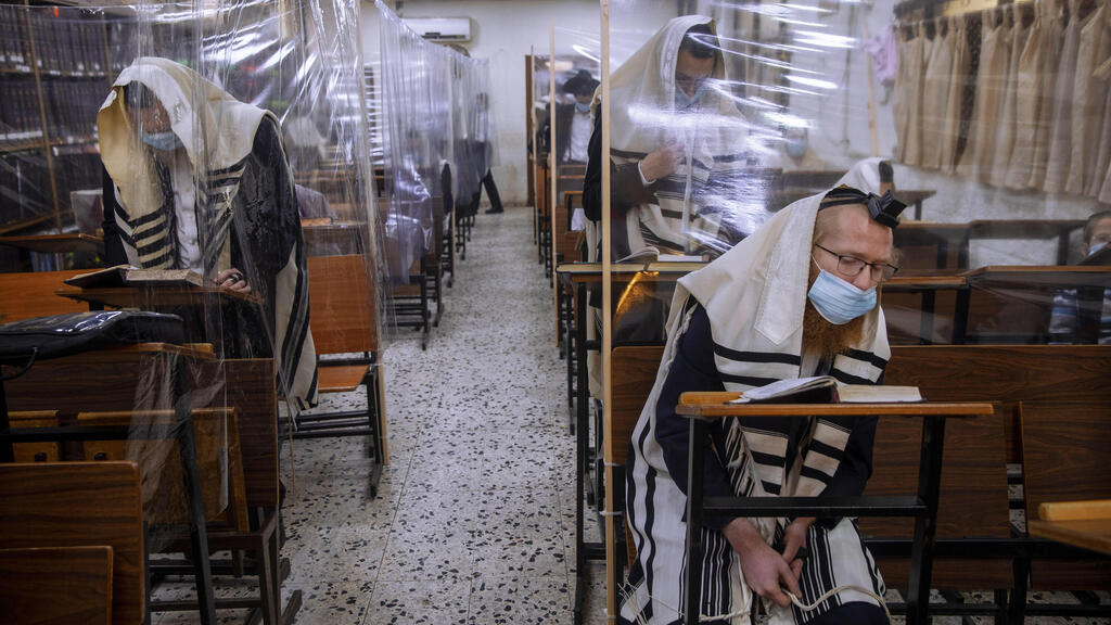  In this Monday, Sept 21, 2020 file photo, ultra-Orthodox Jews wear face masks during a morning prayer in a synagogue separated by plastic partitions, in Bnei Brak 