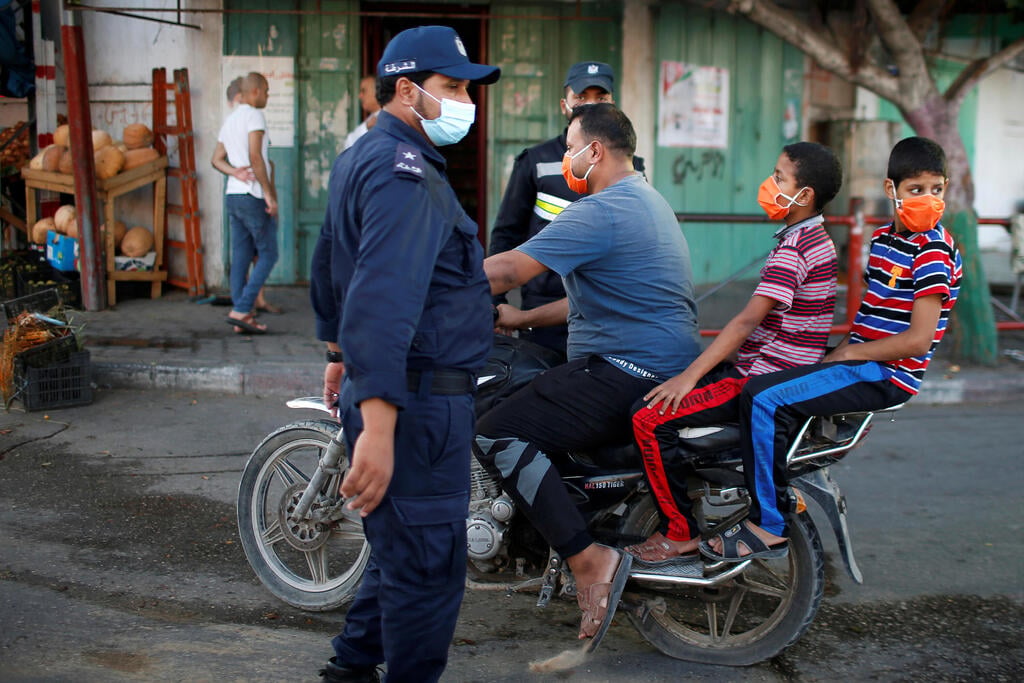 A Palestinian man with his children wearing protective face masks rides his motorcycle by police officers amid the coronavirus pandemic, in the northern Gaza Strip (Photo: Reuters) A Palestinian man with his children wearing protective face masks rides his motorcycle by police officers amid the coronavirus disease (COVID-19) outbreak, in the northern Gaza Strip