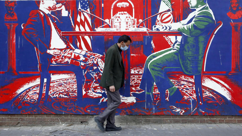 An Iranian man walk past an anti-US wall painting on the wall of former US embassy in Tehran, Iran