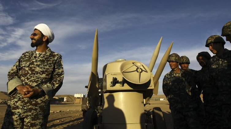 an Iranian clergyman stands next to missiles and army troops, during a manoeuvre, in an undisclosed location in Iran 