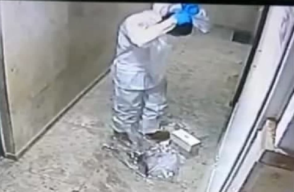 A Magen David Adom worker removes his protective gear before being filmed spitting on images of Jesus and Mary in a Jaffa apartment building (Photo: Screenshot) עובד מד"א תועד יורק על תמונות דתיות נוצריות
