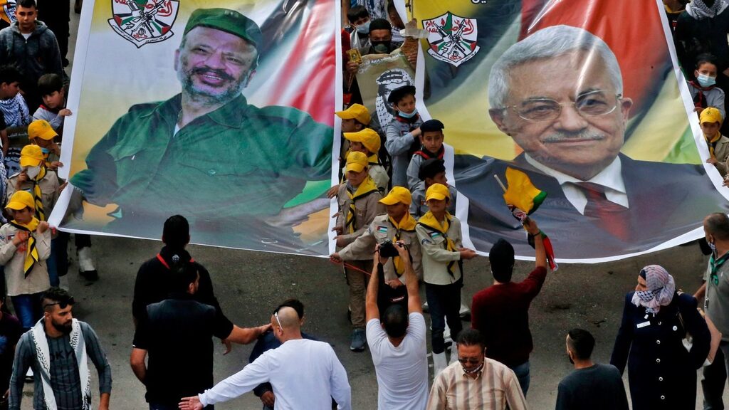 Palestinian Fateh movement supporters carry portraits of their current leader Mahmud Abbas (R) and his late predecessor Yasser Arafat (L) during a march to mark the 16th anniversary of Arafat's death in the village of Dura, near the West Bank city of Hebron 