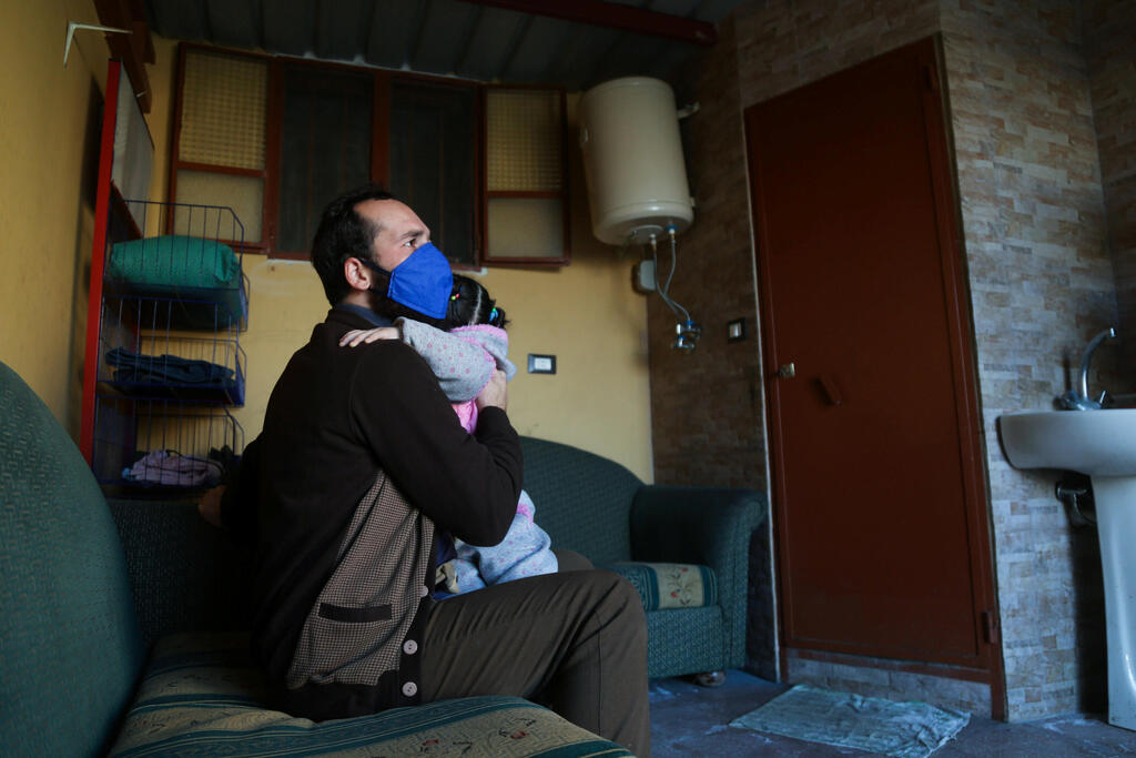 Syrian refugee, Khaled Alyousef, holds his daughter inside his temporary house in the southeastern mountain village of Ketermaya, Lebanon 